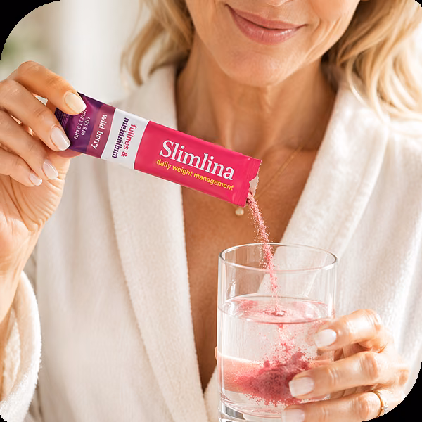 Kvinna som häller innehållet i en portionspåse Slimlina i ett stort glas vatten